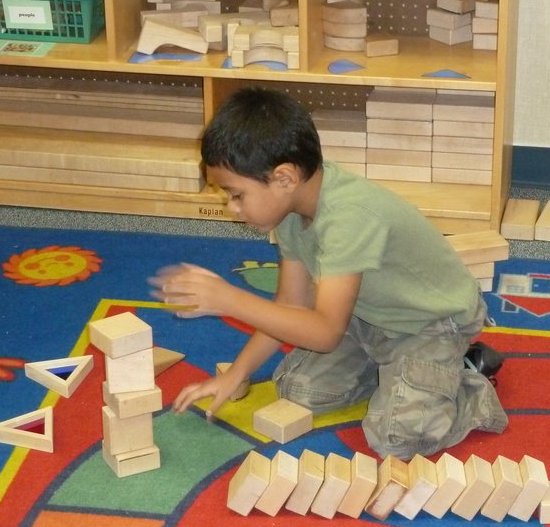 Young child playing with blocks on classroom carpet.